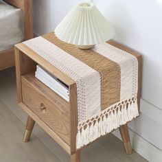 a white lamp sitting on top of a wooden table next to a night stand with books