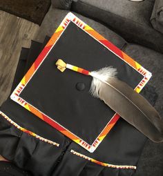 a graduation cap with a feather on it and a placemat in the shape of a square