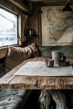 a wooden table with two cups on it in front of a map and couches