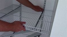 two hands reaching for the bottom shelf of a metal shelving unit