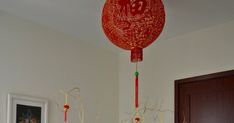 a red paper lantern hanging from the ceiling in a room with white walls and wooden floors