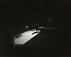 a black and white photo of a person sitting on a bench in the dark,