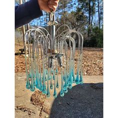 a chandelier with blue glass drops hanging from it's sides in front of some trees