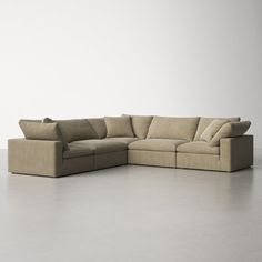 a large sectional couch with pillows on the top and bottom, sitting in front of a white wall