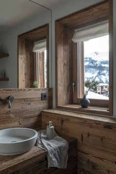 a bathroom sink sitting under a window next to a wooden counter