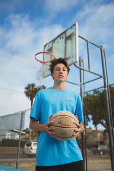 a young man holding a basketball in front of a hoop