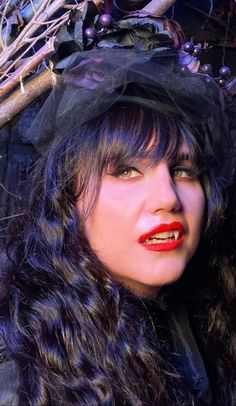 a woman with long hair wearing a black hat and red lipstick is posing for the camera