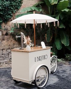 an ice cream cart is decorated with flowers and umbrellas