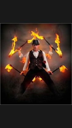 a man holding two fire torches in his hands and wearing a hat on top of his head