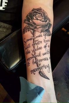 a woman's arm with a rose and some writing on the side of it