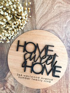 a wooden plaque with the words home sweet home on it next to some dried flowers