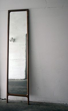 a tall mirror sitting next to a white wall