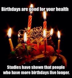 a birthday cake with lit candles and fruit on the table in front of black background