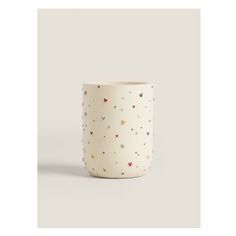 a white cup with small hearts on the outside and inside, sitting in front of a gray background