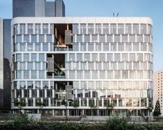 an office building with lots of windows on the front and side of it, surrounded by tall buildings