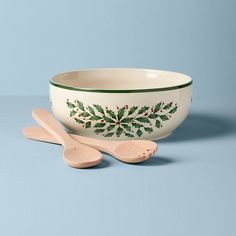 two wooden spoons and a bowl with holly designs