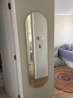 an oval shaped mirror is in the corner of a room with a bed and rug