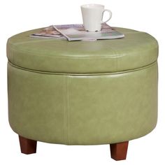 a green ottoman sitting on top of a table next to a cup and saucer