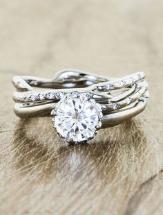 a close up of a ring on top of a wooden table with a diamond in the center