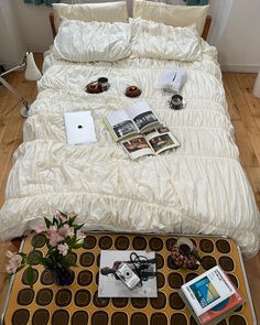 a bed with white comforter and pillows on top of it next to a coffee table