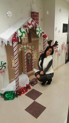 a woman dressed as a reindeer sitting in front of a gingerbread house with candy canes