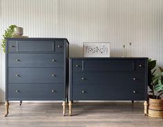 two dark blue dressers with gold handles in a room