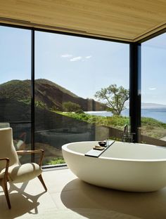 a large white bath tub sitting inside of a bathroom next to a glass wall window