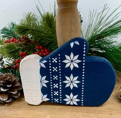 a blue and white wooden heart with snowflakes on it next to pine cones