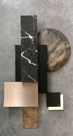 an abstract sculpture made out of wood, marble and metal on a gray surface with a wooden object in the middle