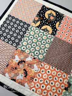 an orange and black patchwork quilt with cats on it