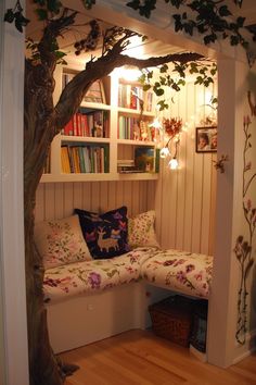 a living room with a couch, bookshelf and tree in the corner next to it