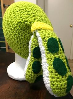 a crocheted green hat on top of a white mannequin head