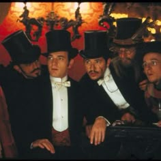 three men in top hats and tails are posing for a photo with another man wearing a suit