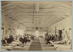 an old black and white photo of people in a room with beds