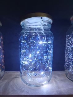 three jars with lights in them sitting on a table