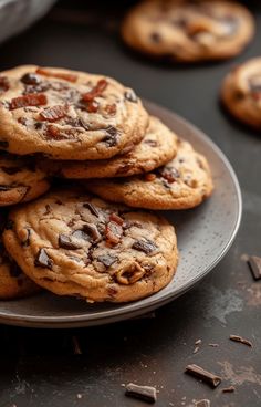 chocolate chip cookies stacked on top of each other in a metal plate with scattered chocolate chips