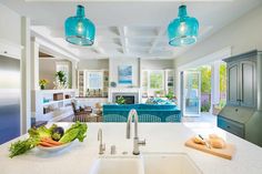 a kitchen with an island, sink and blue glass pendant lights over the stove top