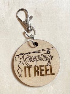 a wooden keychain with the words keeping it reel on it's side