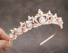 a hand holding a tiara with pearls and crystals on it's headband