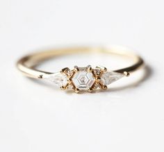 a gold ring with three small white stones on the front and one diamond in the middle