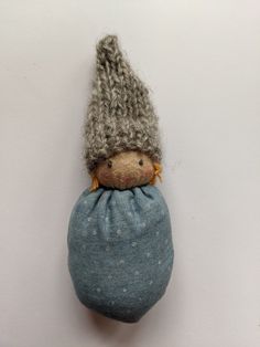 a small stuffed animal with a knitted hat on it's head sitting in a blue bag