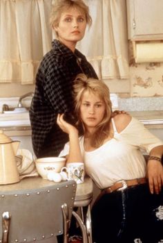 two women sitting at a kitchen table with cups and saucers on the counter top