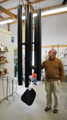 a man standing next to a large black object in a room filled with shelves and chairs