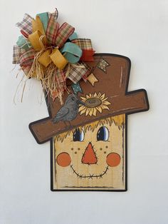 a scarecrow head hanging on the side of a white wall with a sunflower