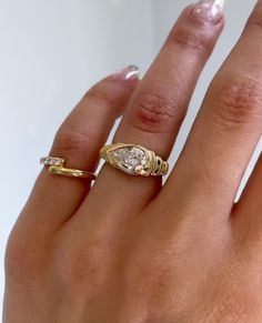 a woman's hand with two gold rings on it and a diamond ring in the middle