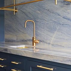 an instagramted photo of a kitchen sink and faucet with gold handles