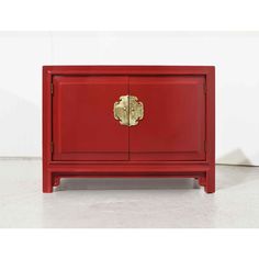 a red cabinet with gold hardware on the front and bottom doors, sitting on a white floor