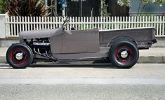 an old car parked on the side of the road in front of a white picket fence