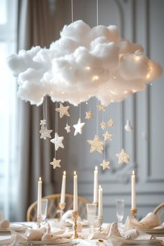 a white cloud with stars hanging from it's sides and candles in the middle