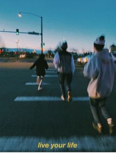 three people walking across a cross walk at an intersection with the words live your life written on it